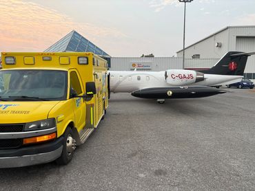 Ambulance stretcher van parked at Ottawa airport, Ontario next to Latitude Air Ambulance plane.