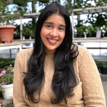 Smiling woman with long hair in a cozy beige sweater.