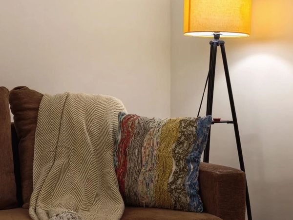 Cozy couch corner with patterned pillow and warm lamp lighting.