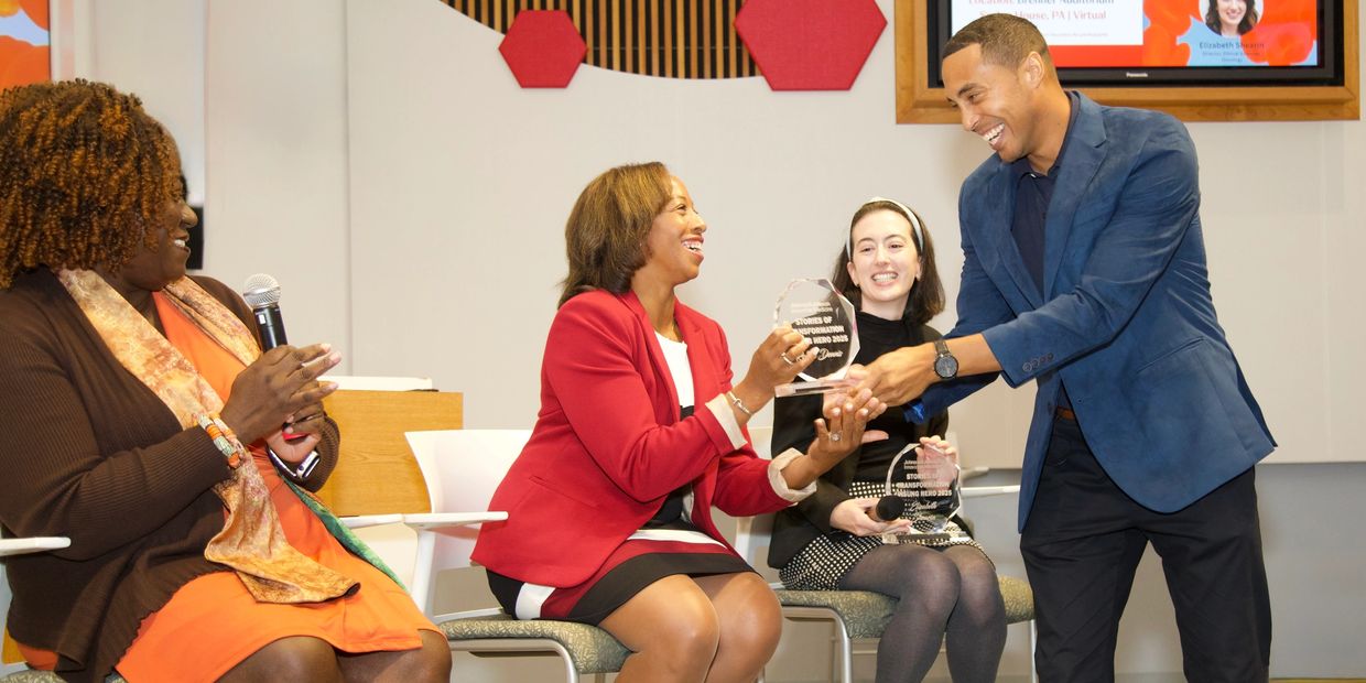 People exchanging awards and smiling during an event.