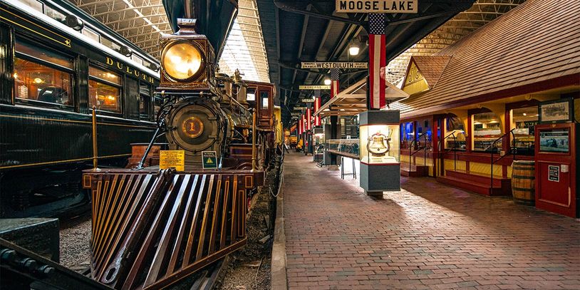 Vintage train engine inside a museum with signs above.