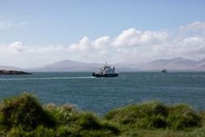 A ship sailing on a calm sea with mountains in the background.