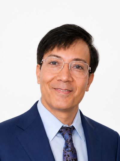 Smiling man in a blue suit and glasses.