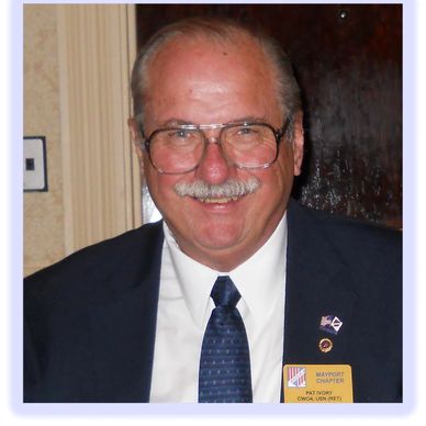 Smiling older man in glasses and suit with tie.