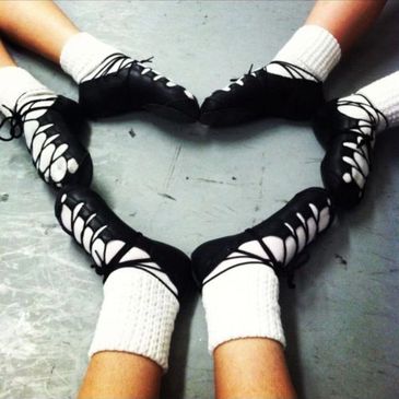 Three Irish dancers wearing ghillies and poodle socks with feet in heart shape
