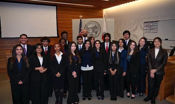 A diverse group of young professionals posing in a courtroom setting.