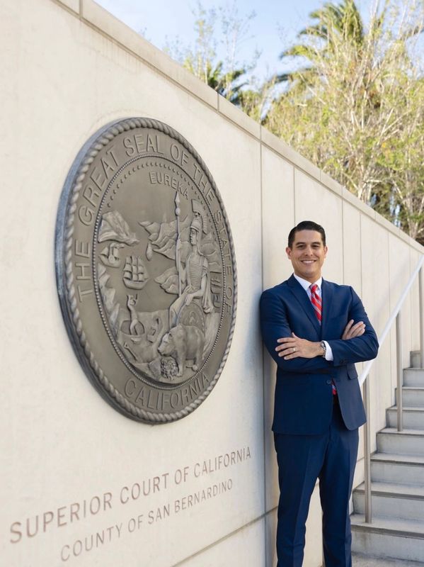 Man in suit standing by California Superior Court seal.