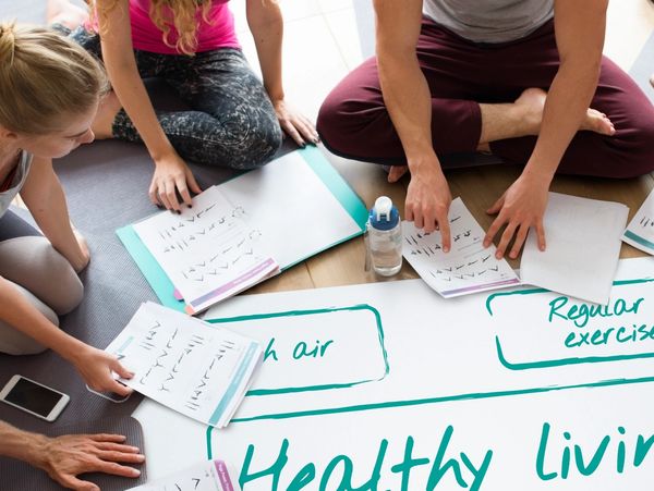 Group sitting on floor discussing healthy living with notes and charts.