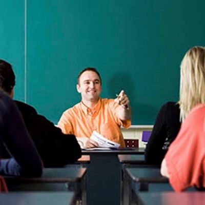 Teacher pointing and smiling while seated at the head of the classroom