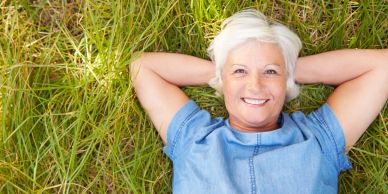Femme âgée souriante allongée sur l'herbe.