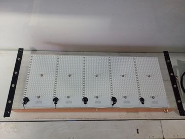 A row of six white electronic devices with knobs and screws on a flat surface.
