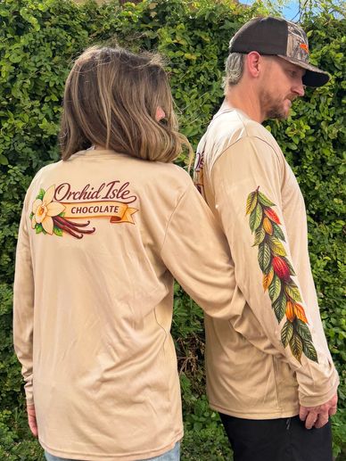 Two people wearing matching beige long-sleeve shirts with the text "Orchid Isle Chocolate."