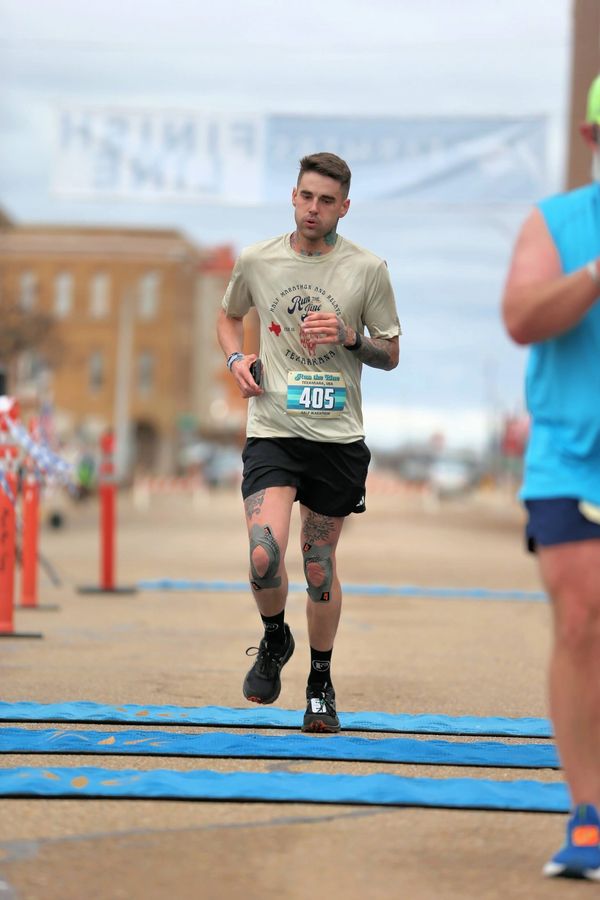 Runner with knee braces crosses the finish line in a race.