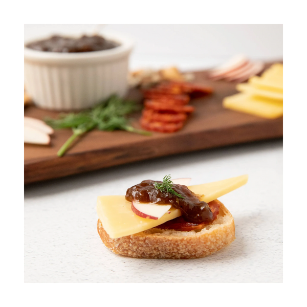 Gourmet crostini topped with cheese, apple slices, chutney, and herbs.