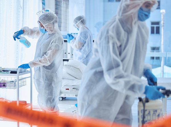 Healthcare workers in protective suits disinfect a medical facility.