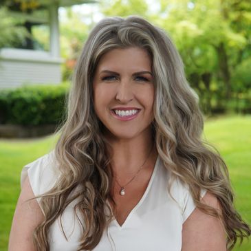 Woman with long wavy blonde hair smiling outdoors.