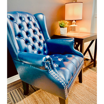 Elegant blue leather armchair with button tufting and nailhead trim.