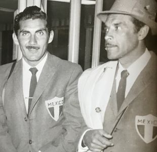 Two men wearing Mexico sports blazers, one in a hat.