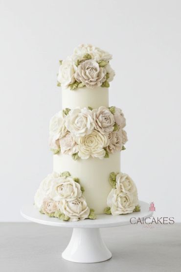 Elegant three-tiered white cake decorated with creamy flower designs.