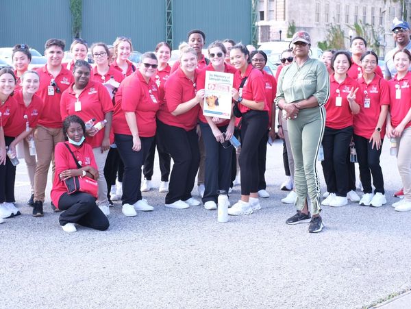 Group of people in red shirts gathered outdoors, holding a memorial sign.