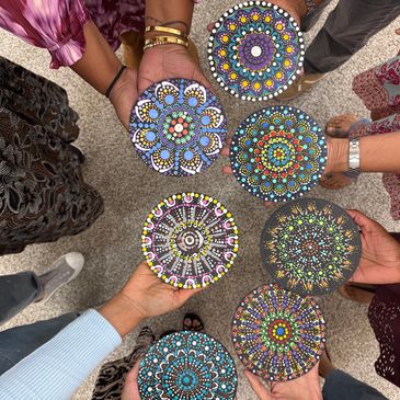 Hands holding colorful dot mandala painting pieces.