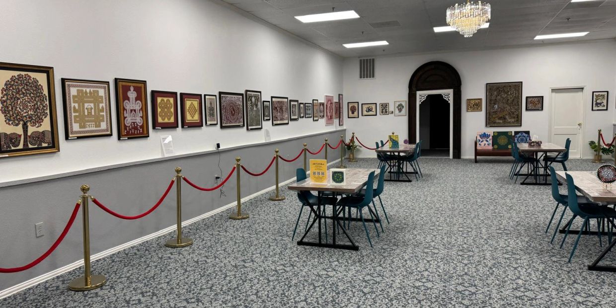 Gallery room with framed artwork on walls and tables with chairs.