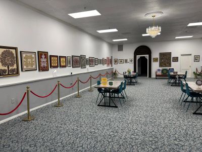 Gallery room with framed artwork on walls and tables with chairs.