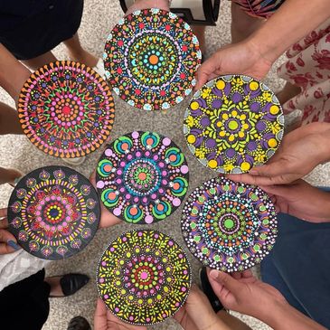 Hands holding colorful circular mandala art pieces with intricate patterns.
