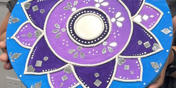 Colorful rangoli design with purple, blue, and silver accents.