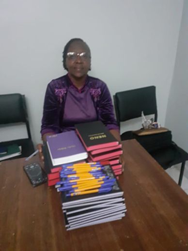 a woman sitting with books in the table.