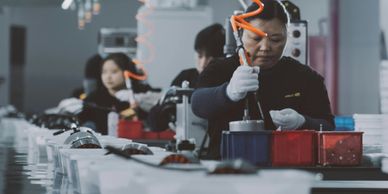 Workers assembling products on a factory line with focused attention.