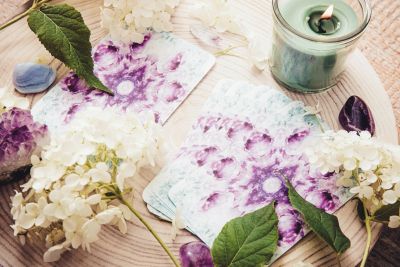 Floral tarot cards with crystals and a candle.