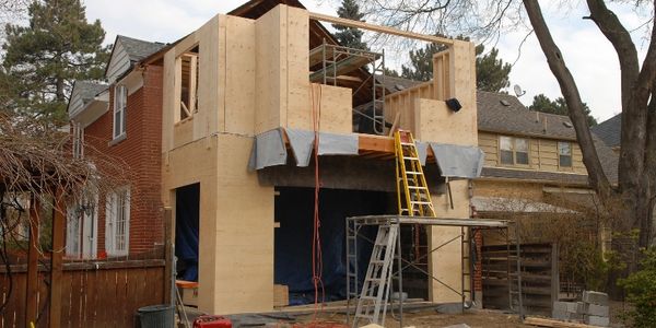 Wooden frame construction of a house extension in progress.