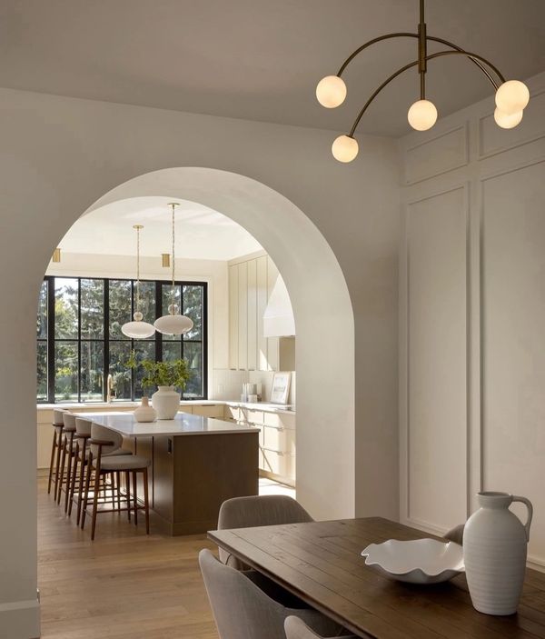 Modern kitchen and dining area with warm wood tones and soft lighting, & barrel vault arched opening