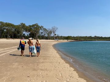 Three friends walking along a sandy beach on a sunny day.