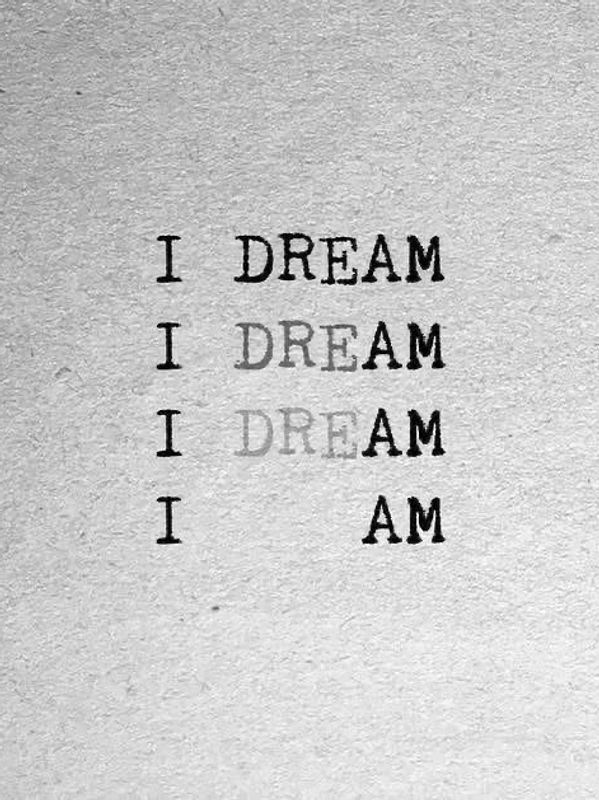 Text fading from 'I DREAM' to 'I AM' on textured paper.
