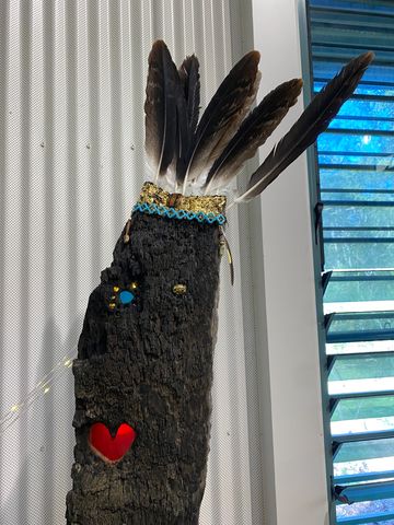 Decorative wooden sculpture with feathers and a heart-shaped detail.