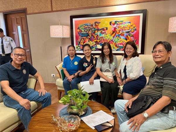 Group of six people sitting and smiling in a warmly lit room with colorful artwork.