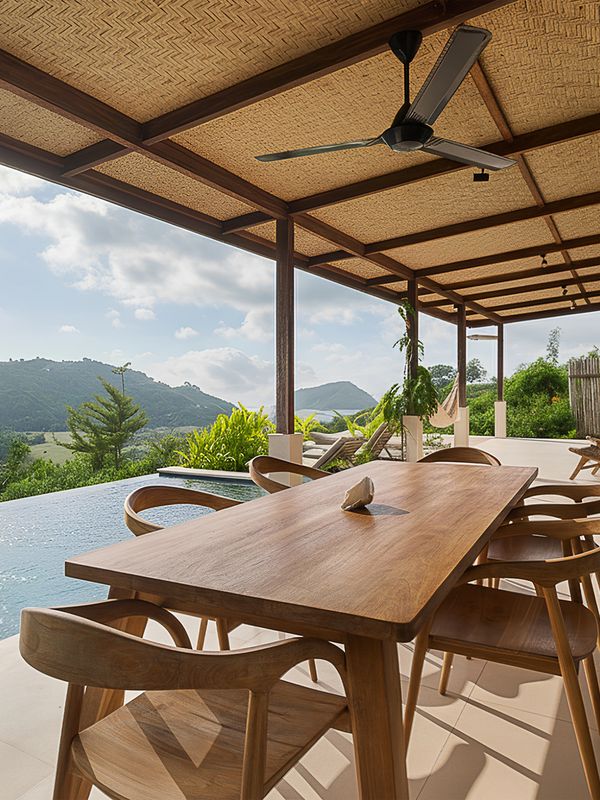 Outdoor dining area with wooden furniture overlooking a scenic mountain view.