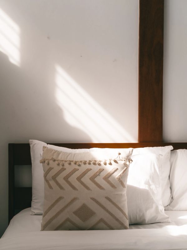 Decorative pillow with geometric design on a neatly made bed.