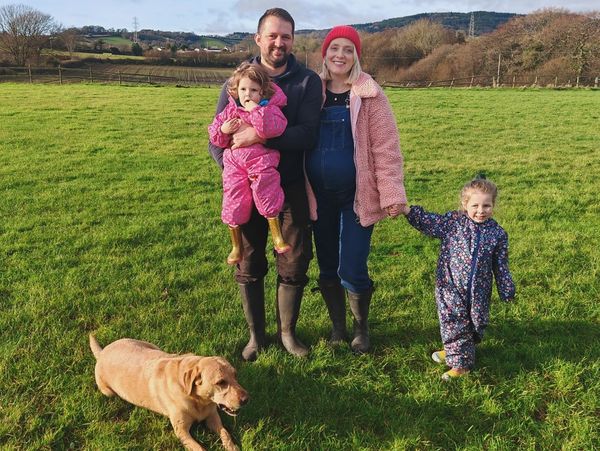 A happy family with two children and a dog in a green field.