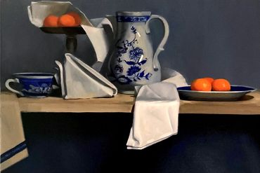 Still life with blue and white ceramics and bright oranges on a wooden table.