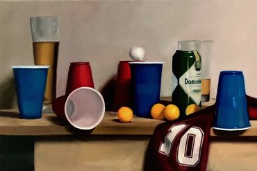 A party scene with cups, ping pong balls, and a jersey on a table.