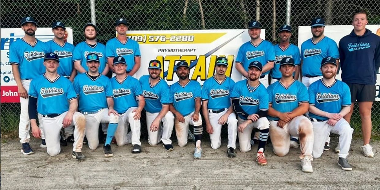 Baseball team in blue jerseys posing together outdoors on dirt ground.