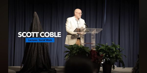 Scott Coble lecturing on social work at a podium.