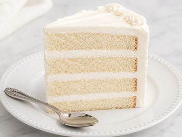 A slice of white layered cake with frosting.