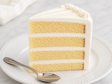 A slice of layered vanilla cake with white frosting.