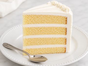 A slice of layered vanilla cake with white frosting.