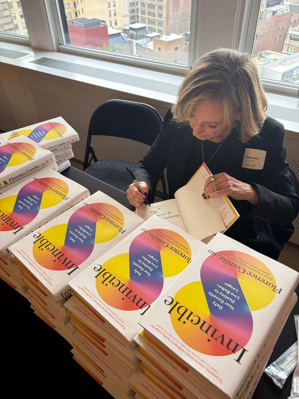 Author Florence Comite signs copies of her book "Invincible" at a book signing event.