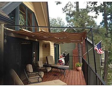 Cozy porch with chairs, a table, and an American flag in a wooded neighborhood.